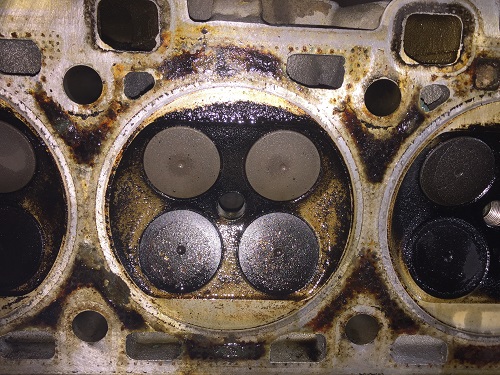 A four-valve engine cylinder head with carbon deposits. Concept image of ‘Cleaning Your Engine By Decarbonization: Does It Matter?” | Sean’s Auto Care in Van Nuys, CA.