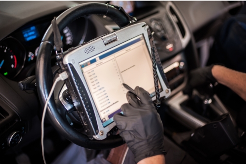 Vehicle diagnostics in Van Nuys, CA with Sean's Auto Care. Image of mechanic using diagnostics machine while sitting in front seat of a car in the shop.