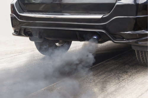 Emission system check service near me in Los Angeles and Van Nuys, CA with Sean’s Auto Care. Image of a black car emitting smoke from its exhaust pipe, indicating a potential emissions system issue.