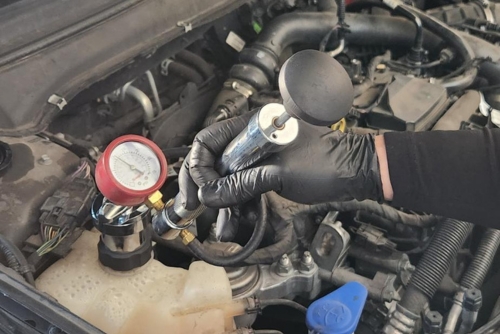 Cooling system service near me in Los Angeles and Van Nuys, CA with Sean’s Auto Care. Image of an open hood car with a mechanic's hands working on the cooling system.