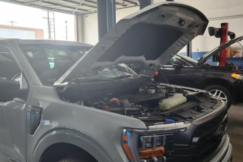Emission system repair near me in Los Angeles and Van Nuys, CA with Sean’s Auto Care. Image of a grey car with its hood open at Sean's Auto Care in Van Nuys, CA, undergoing emissions system repair.