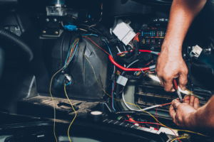 Auto Electrical Repair in Van Nuys, CA with Sean's Auto Repair. Image of mechanic hand holding tiny tools to perform electrical repair near wires on car.