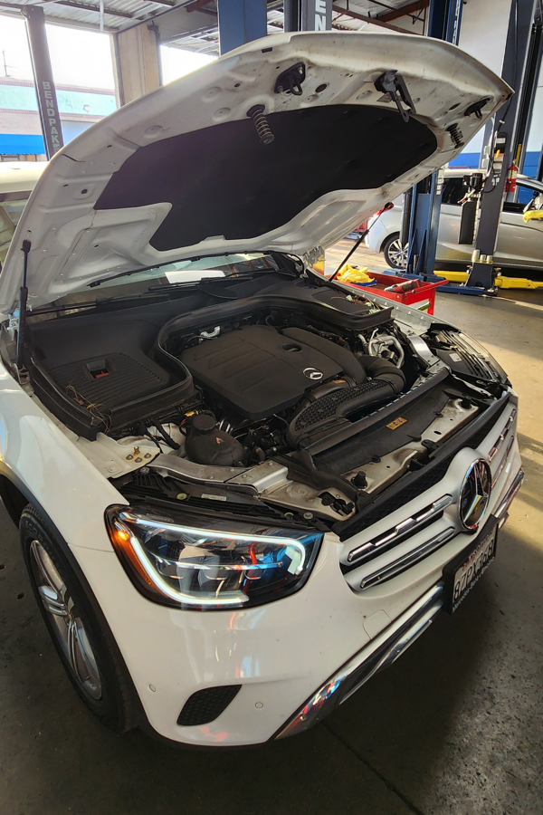 Mercedes A and B services in Van Nuys, CA with Sean's Auto Care. Image of white Mercedes Benz with hood open for maintenance services in the shop.