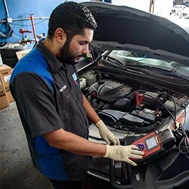 Male mechanic performing diagnostics on a car that came in for maintenance services in Van Nuys, CA at Sean's Auto Care.