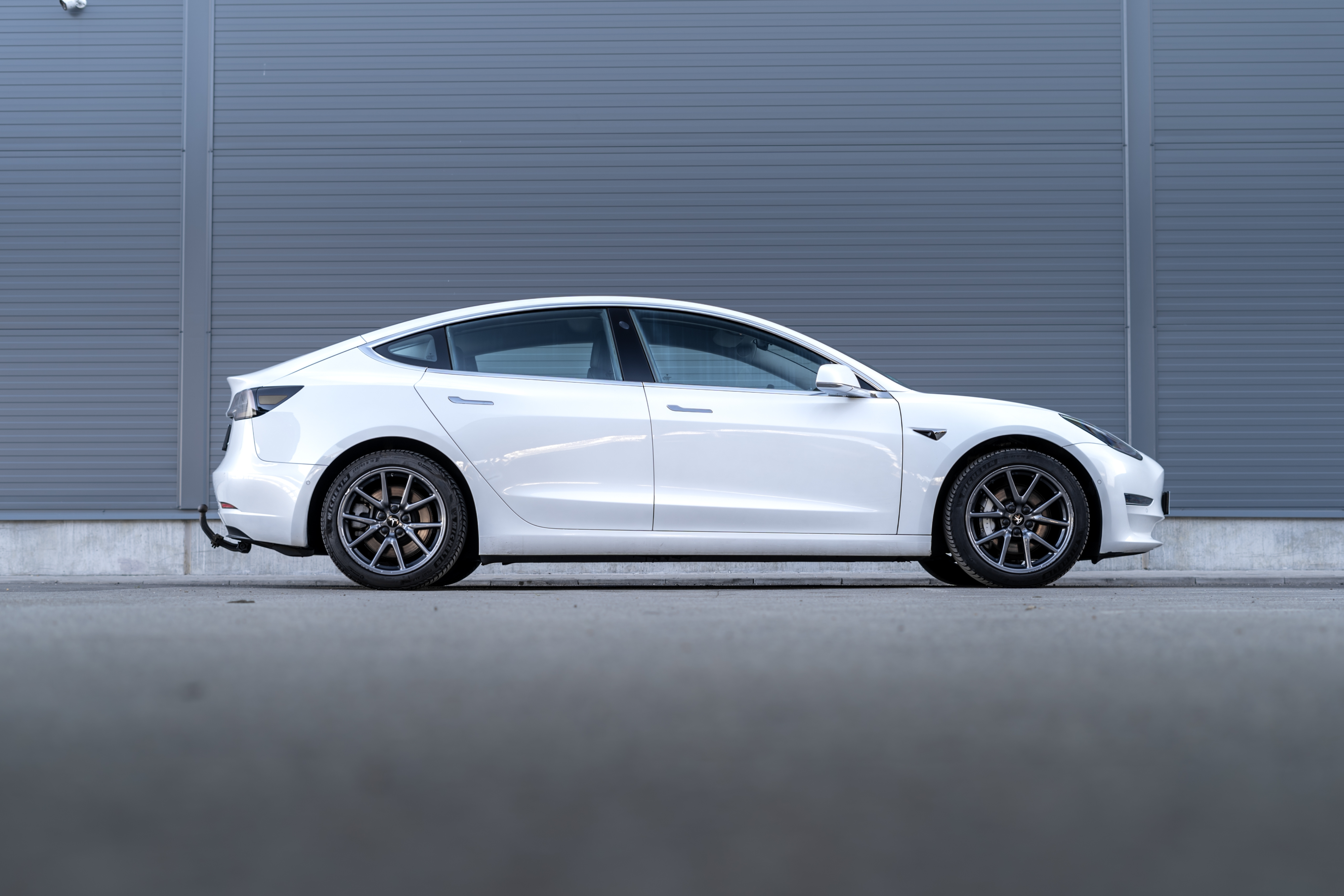 Tesla service and Tesla maintenance in Van Nuys, CA with Sean's Auto Care. Image of white Tesla vehicle parked on the side of a gray building.