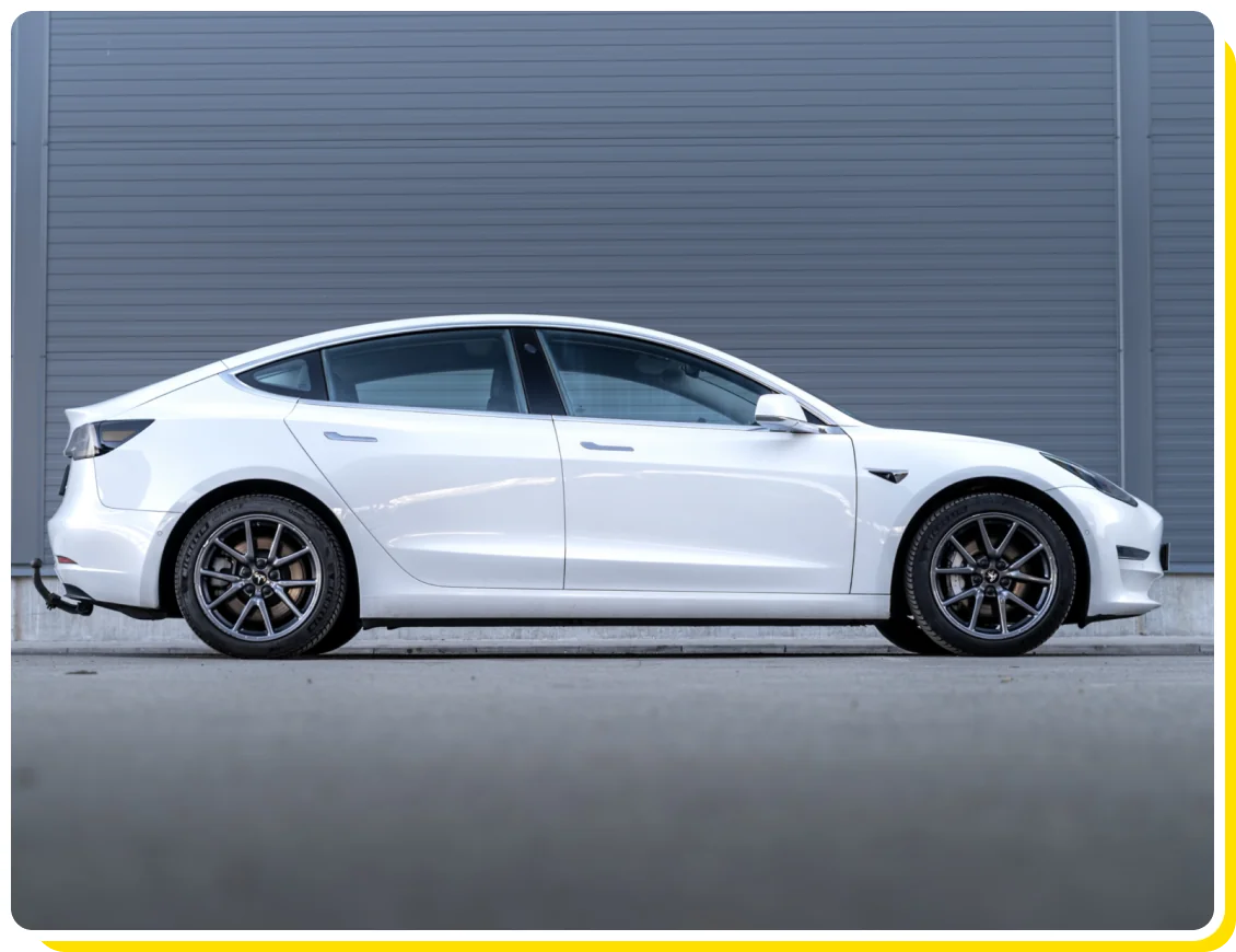 Tesla service and Tesla maintenance in Van Nuys, CA with Sean's Auto Care. Image of white Tesla vehicle parked on the side of a gray building.